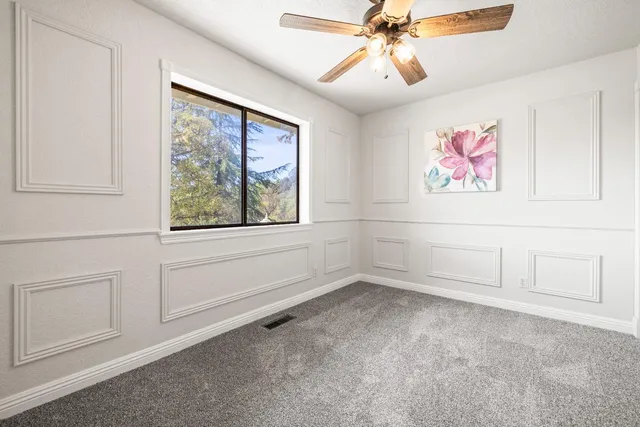 an empty room with windows and fan