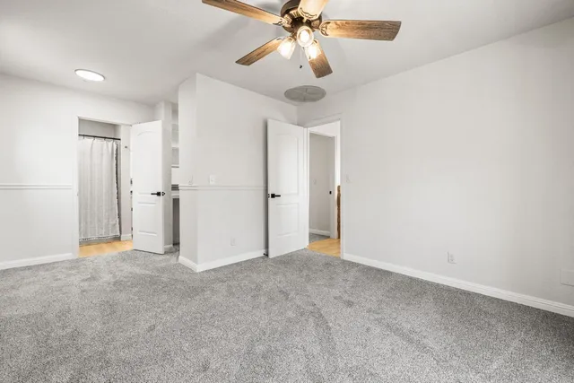 an empty room with closet and a ceiling fan