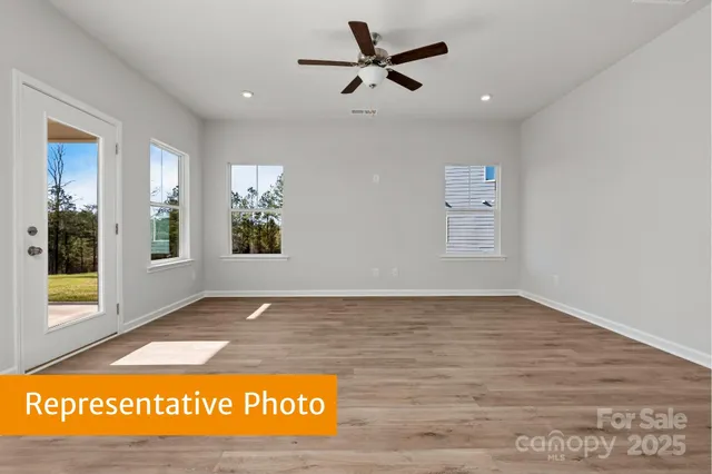 a view of kitchen and empty room with wooden floor