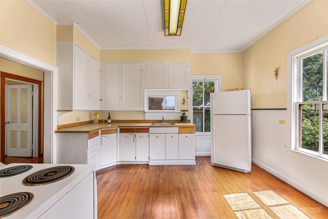 a kitchen with a refrigerator a stove top oven a counter space and wooden floor