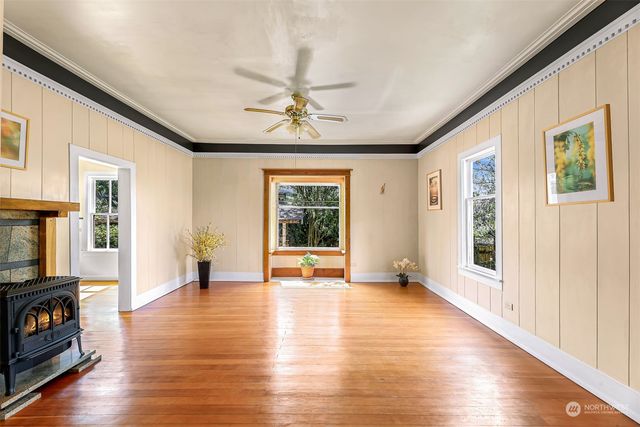 a view of an empty room with window and wooden floor