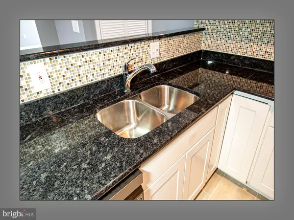 a bathroom with a granite countertop sink a mirror and shower