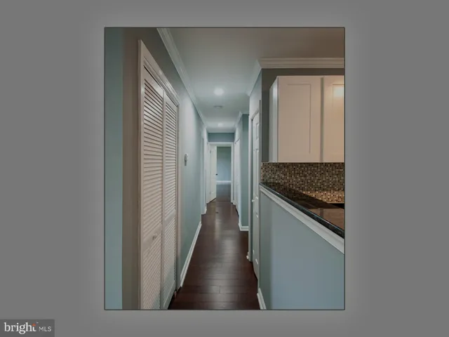 a view of a hallway to a livingroom and a kitchen with a sink