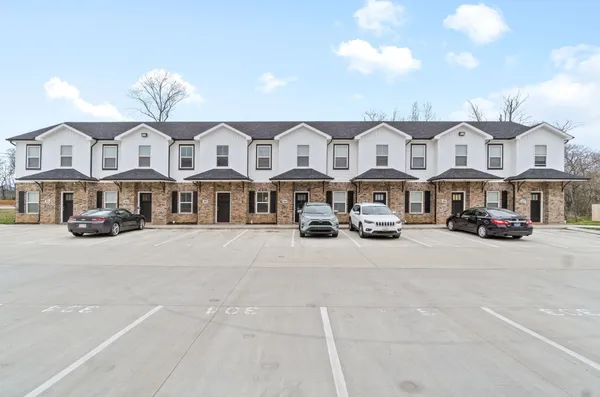 a front view of a building with lot of cars parked on road