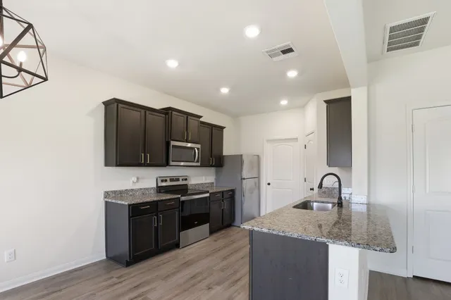 a kitchen with stainless steel appliances granite countertop a sink stove and refrigerator