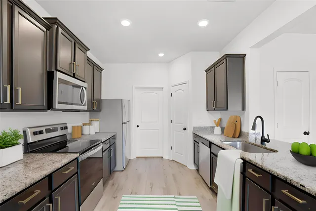 a kitchen with stainless steel appliances granite countertop a sink stove and refrigerator