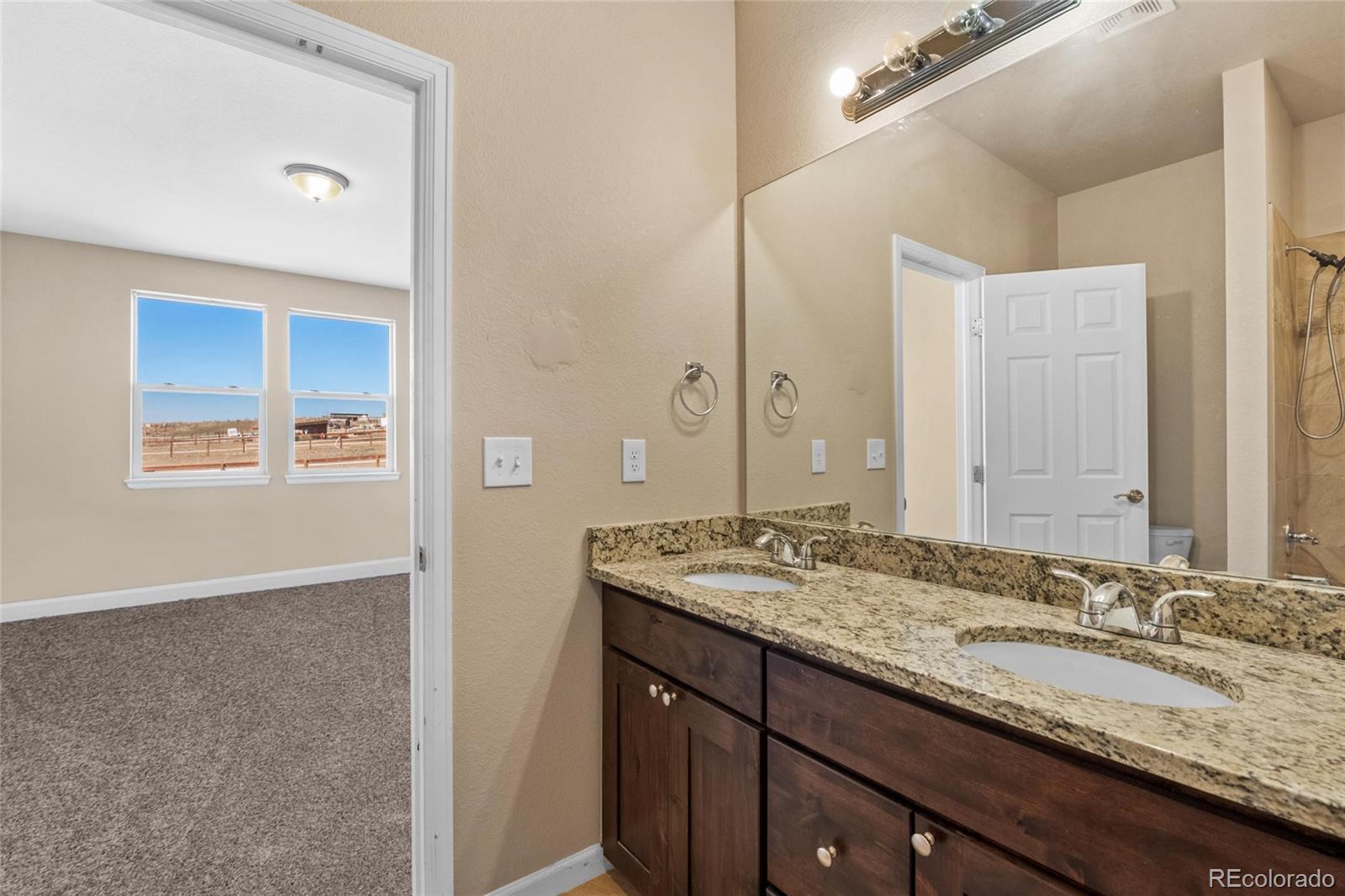 1445 4th Place Deer Trail, CO 80105 - Photo 16 of 19 a bathroom with a granite countertop double vanity sink and a mirror