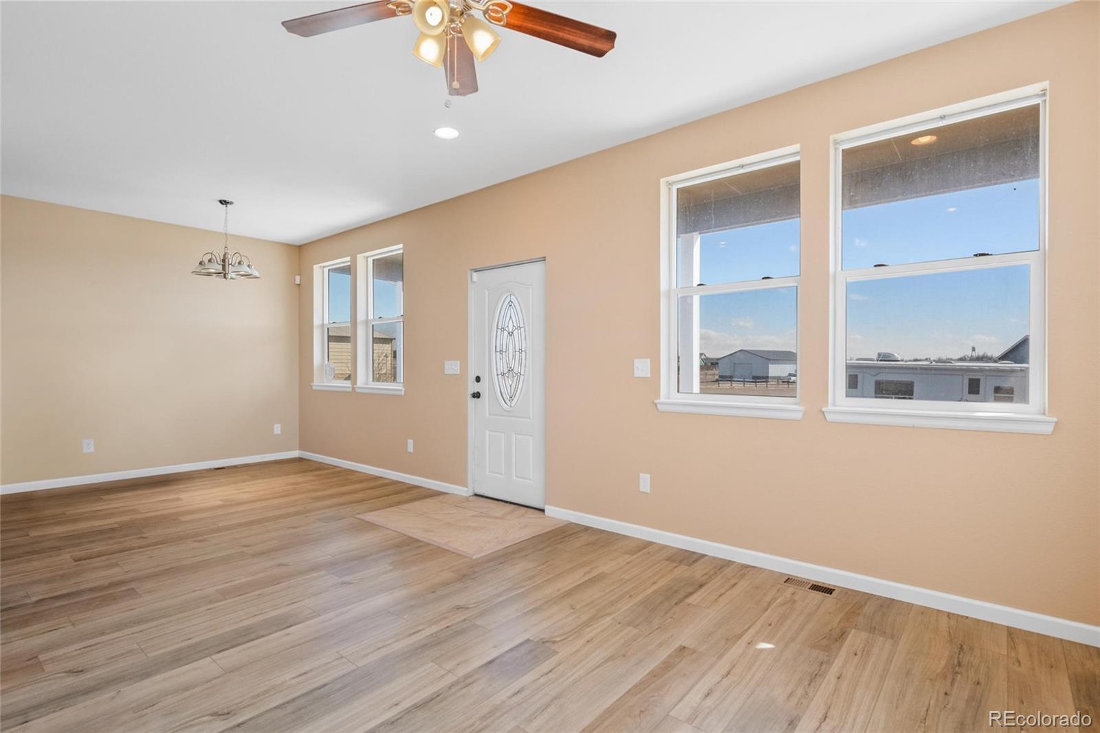 1445 4th Place Deer Trail, CO 80105 - Photo 3 of 19 an empty room with wooden floor and windows