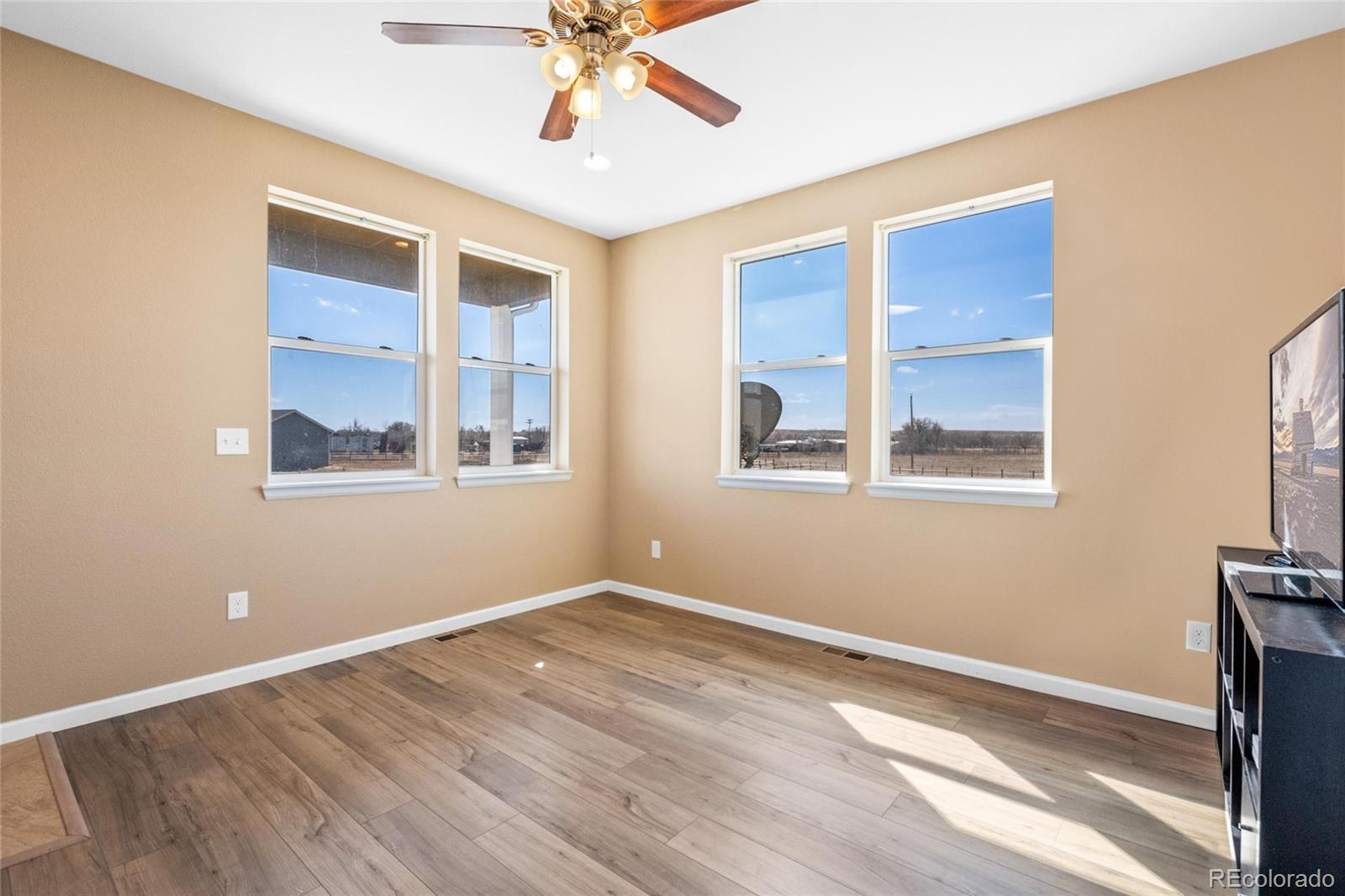 1445 4th Place Deer Trail, CO 80105 - Photo 5 of 19 a view of an empty room with a window and wooden floor