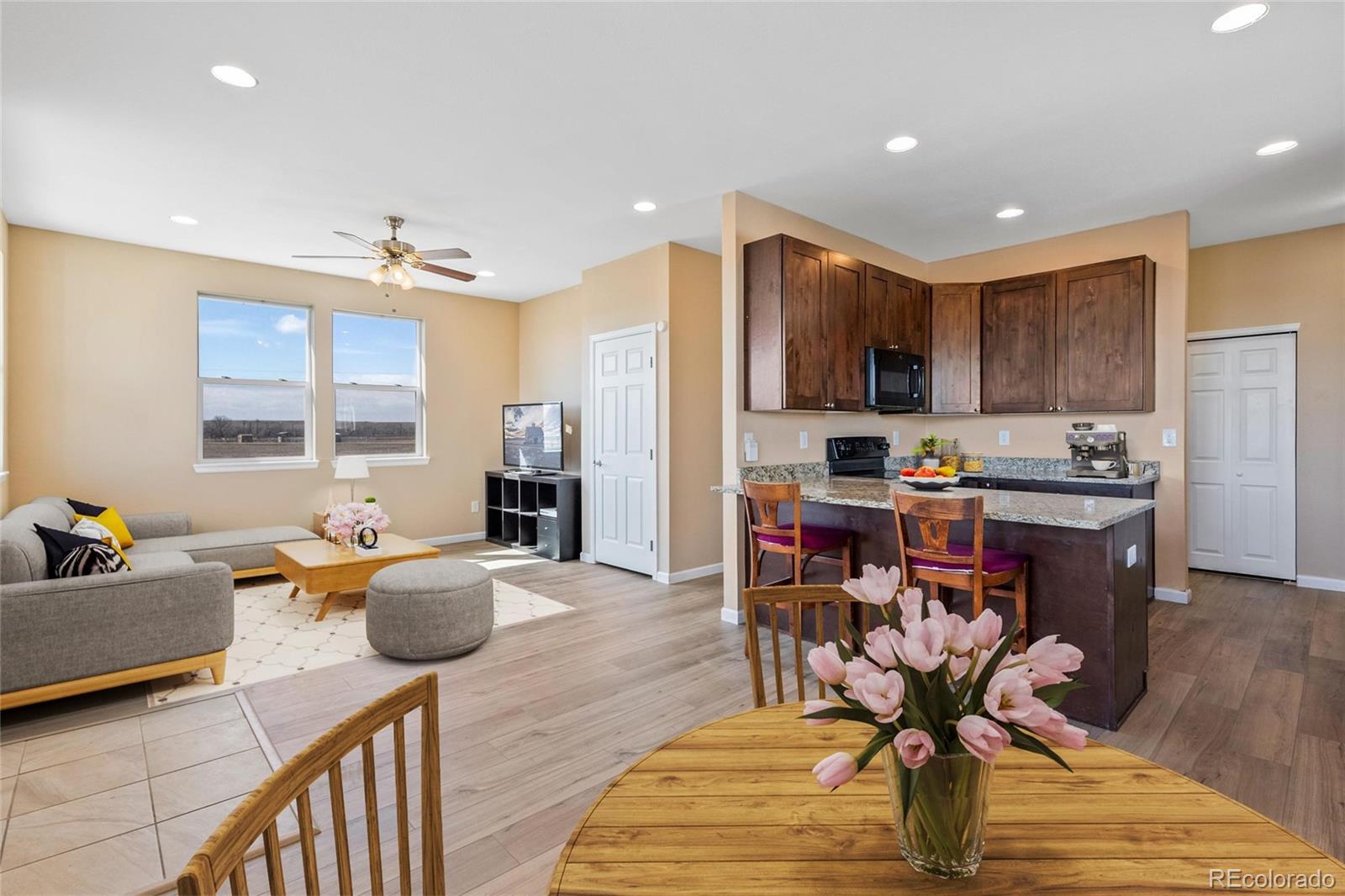 1445 4th Place Deer Trail, CO 80105 - Photo 6 of 19 a kitchen with stainless steel appliances granite countertop a refrigerator a stove a sink a dining table and chairs with wooden floor