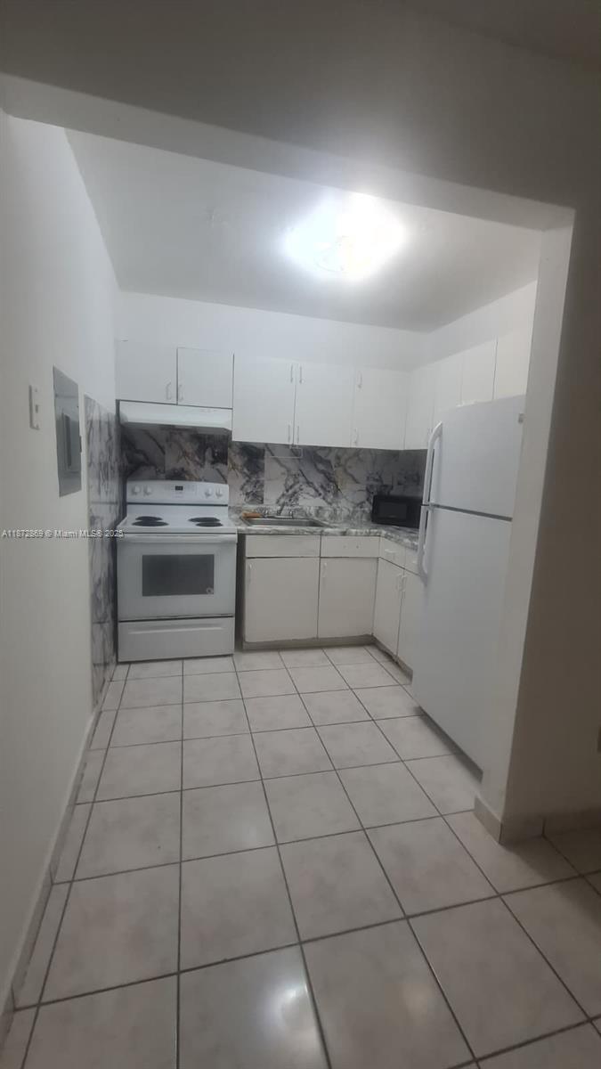 3640 Northwest 9th Street, Unit 105 Miami, FL 33125 - Photo 12 of 31 a kitchen with granite countertop a refrigerator and a stove top oven