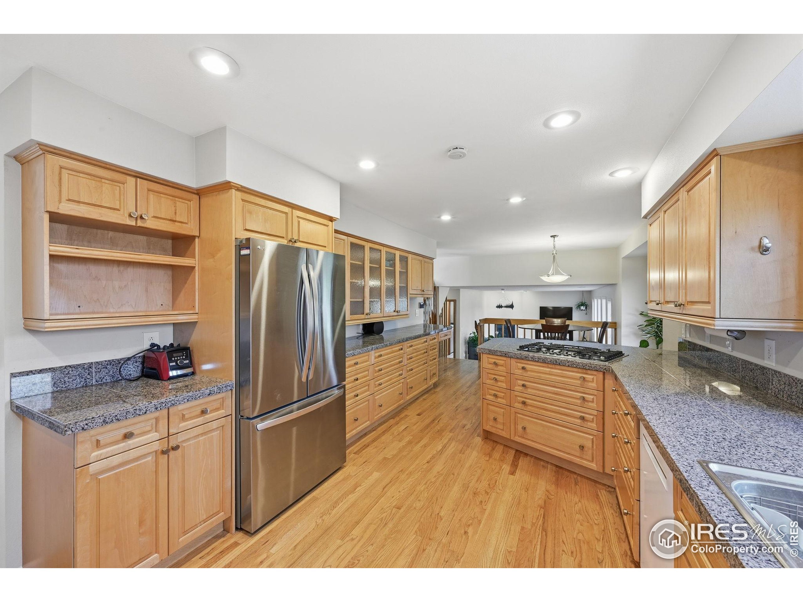 2158 Rockspray Court Longmont, CO 80503 - Photo 14 of 35 a kitchen with stainless steel appliances granite countertop a refrigerator a sink dishwasher a stove and white countertops with wooden floor