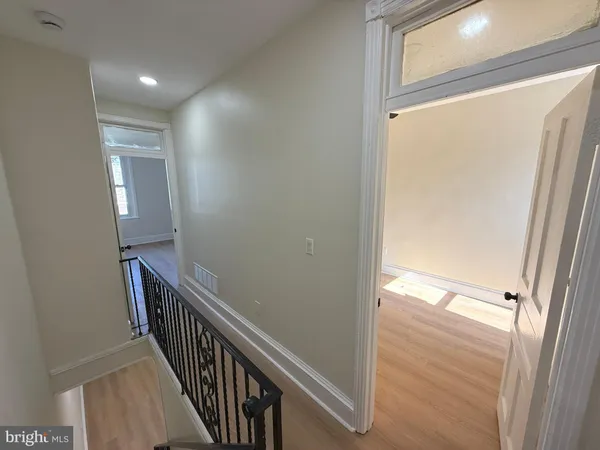 a view of a hallway with wooden floor and a door