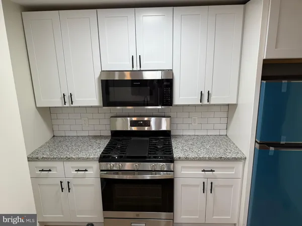 a kitchen with stainless steel appliances granite countertop white cabinets and a stove