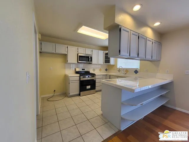 a kitchen with granite countertop a sink a stove top oven and cabinetry