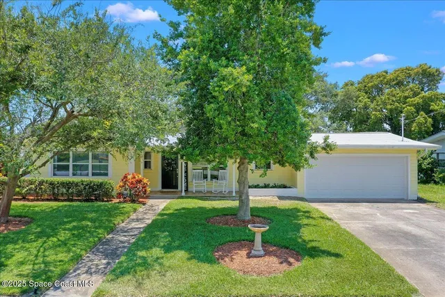 a front view of a house with garden and trees