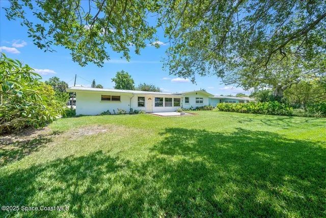 a view of a big house with a big yard and large trees