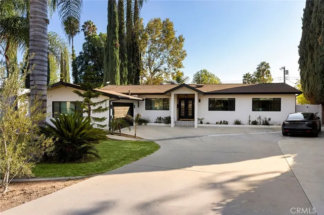 a view of a white house with a yard and table and chairs under an umbrella