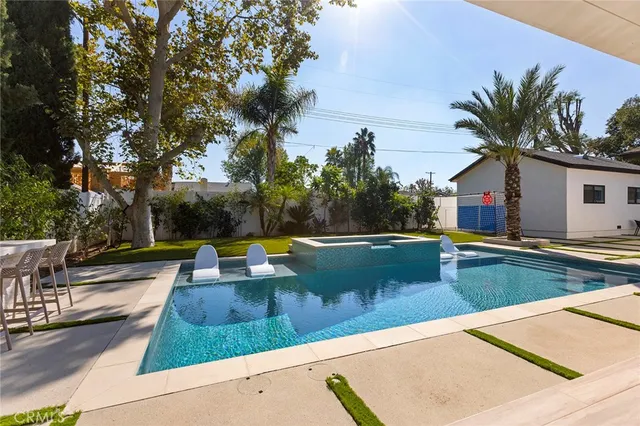 a view of swimming pool with lawn chairs and plants