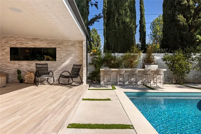 a view of swimming pool with lawn chairs and plants