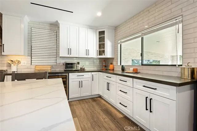 a kitchen with granite countertop white cabinets white appliances a sink and a large window