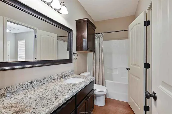 a bathroom with a granite countertop sink toilet and shower