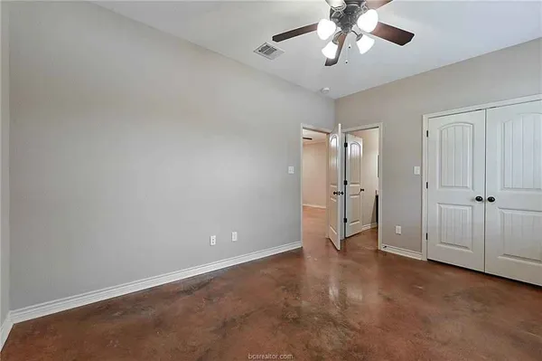 an empty room with chandelier fan and windows