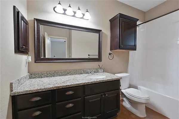 a bathroom with a granite countertop toilet sink and mirror