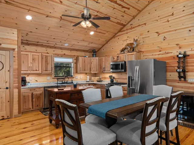 a kitchen with stainless steel appliances kitchen island granite countertop a table chairs and a refrigerator