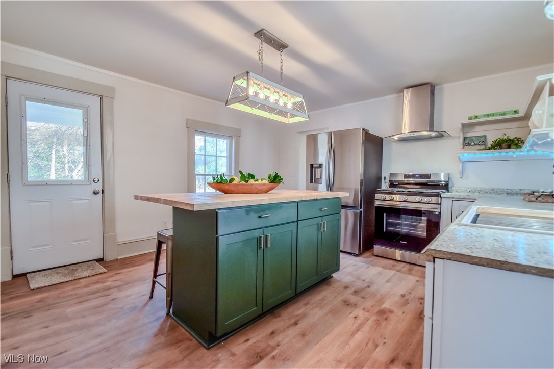 6416 Chapel Road Madison, OH 44057 - Photo 12 of 35 Kitchen with a sink, wall chimney range hood, stainless steel appliances, green cabinets, and light wood finished floors