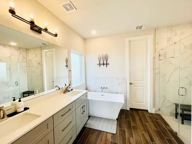 a spacious bathroom with a double vanity sink a mirror and a shower