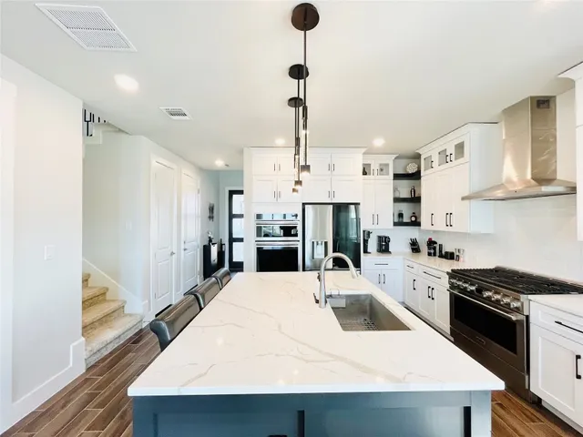 a kitchen with stainless steel appliances kitchen island granite countertop a sink a stove and a refrigerator