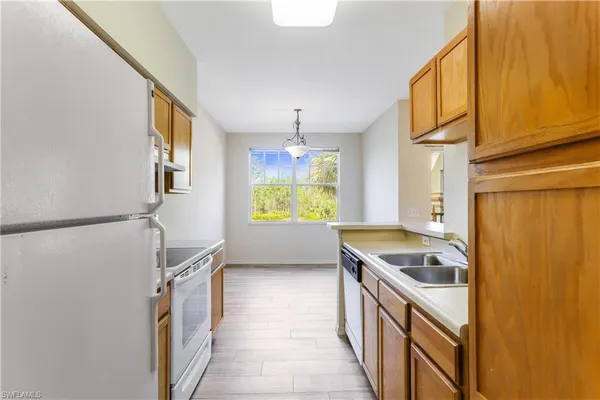 a kitchen with granite countertop a refrigerator a sink dishwasher stove and oven