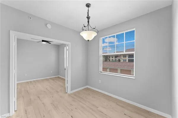 an empty room with wooden floor cabinet and windows
