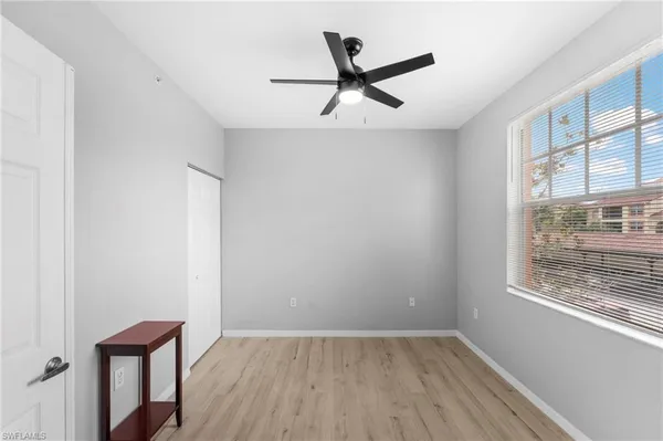 an empty room with wooden floor fan and windows