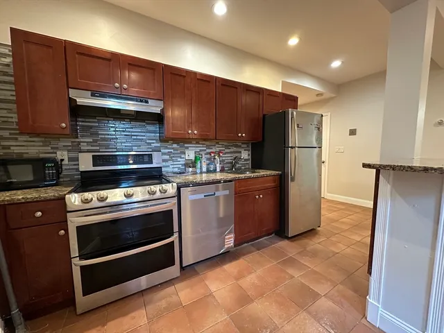 a kitchen with stainless steel appliances granite countertop a stove a refrigerator and a sink