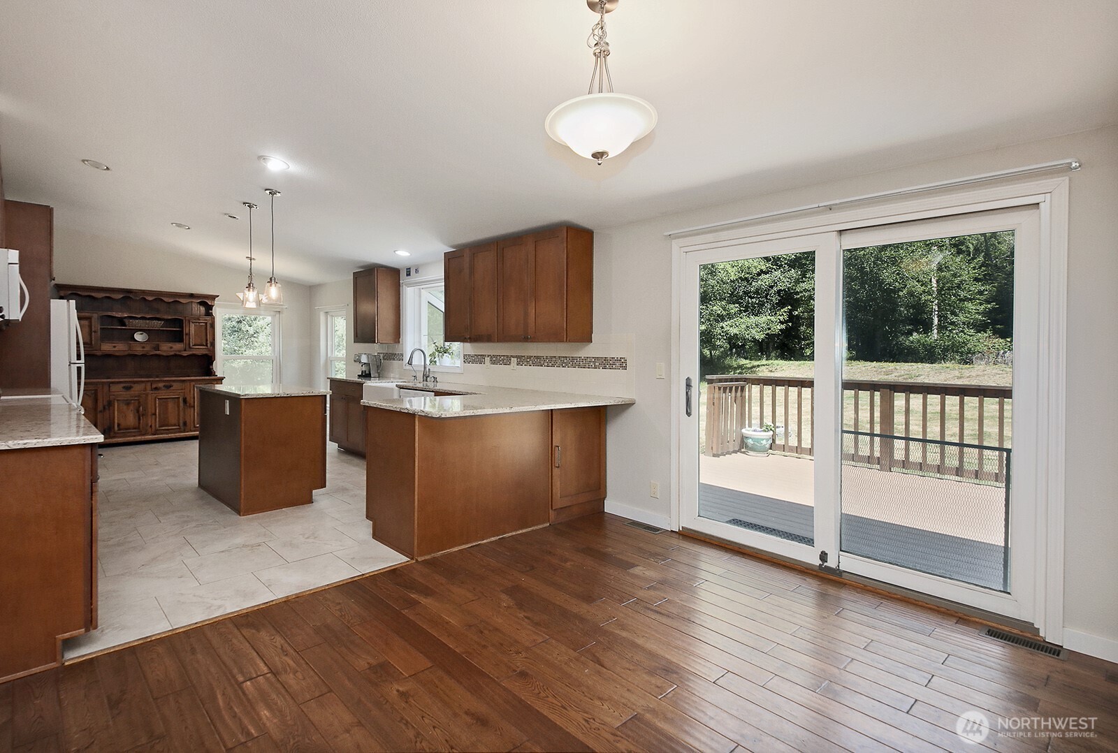 1677 Lancaster Road Freeland, WA 98249 - Photo 11 of 40 a kitchen with stainless steel appliances granite countertop a stove top oven a sink dishwasher a refrigerator and a dining table with wooden floor