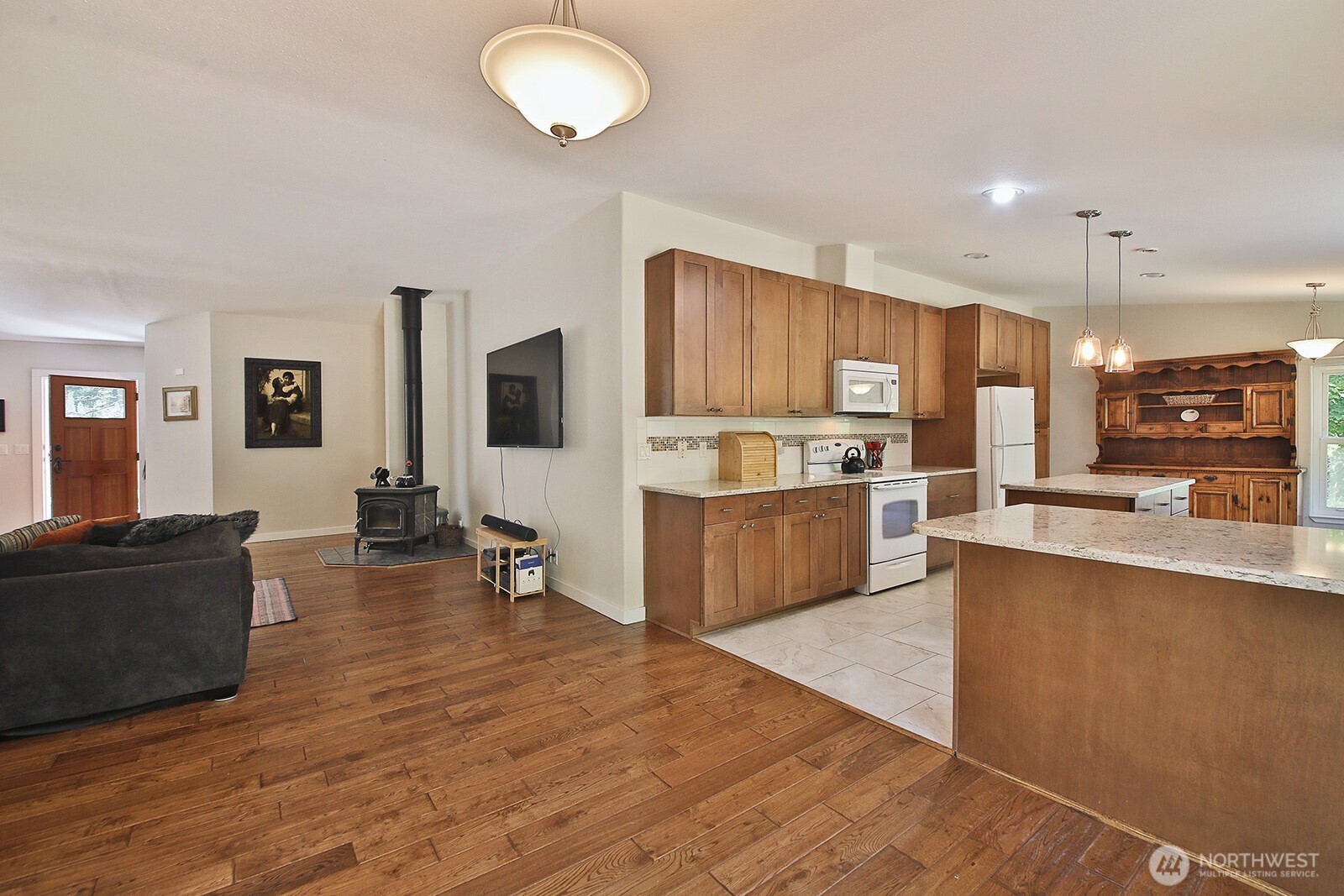 1677 Lancaster Road Freeland, WA 98249 - Photo 22 of 40 a kitchen with stainless steel appliances kitchen island granite countertop a stove top oven a sink a refrigerator white cabinets and wooden floor