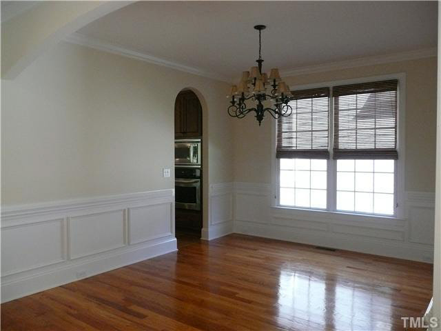 7333 Newport Avenue Raleigh, NC 27613 - Photo 4 of 20 an empty room with wooden floor chandelier and windows