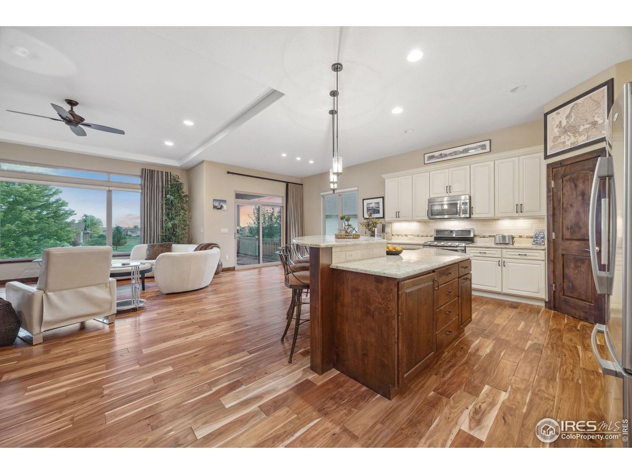 6178 Bay Meadows Drive Windsor, CO 80550 - Photo 11 of 40 a living room with stainless steel appliances kitchen island granite countertop a refrigerator a stove top oven a sink dishwasher and white cabinets with wooden floor