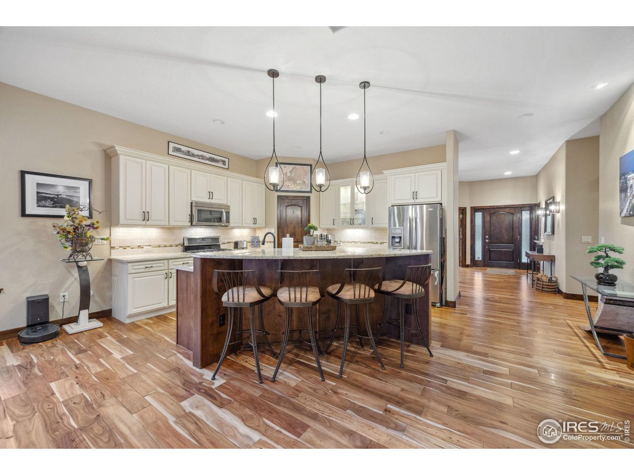 6178 Bay Meadows Drive Windsor, CO 80550 - Photo 13 of 40 a kitchen with stainless steel appliances kitchen island granite countertop a table chairs and a refrigerator