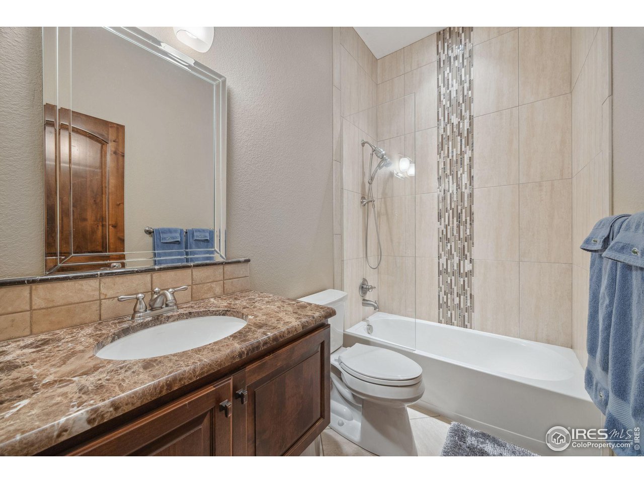 6178 Bay Meadows Drive Windsor, CO 80550 - Photo 25 of 40 a bathroom with a granite countertop sink toilet a large mirror a bathtub and shower