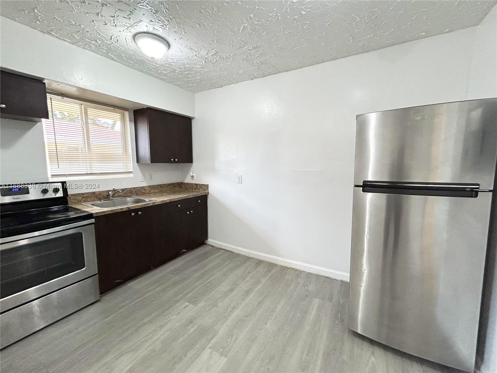 651 Northeast 86th Street, Unit 3 Miami, FL 33138 - Photo 2 of 11 a kitchen with a refrigerator and a stove top oven