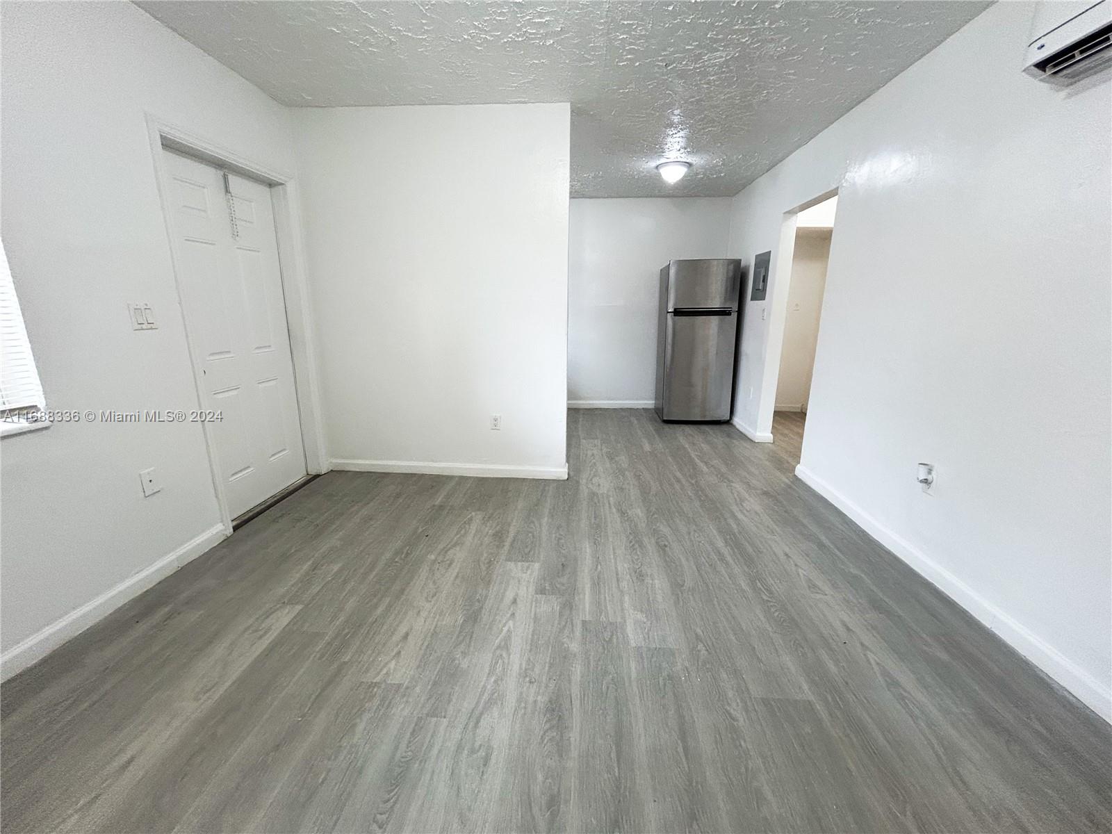 651 Northeast 86th Street, Unit 3 Miami, FL 33138 - Photo 4 of 11 a view of a big room with wooden floor and a kitchen
