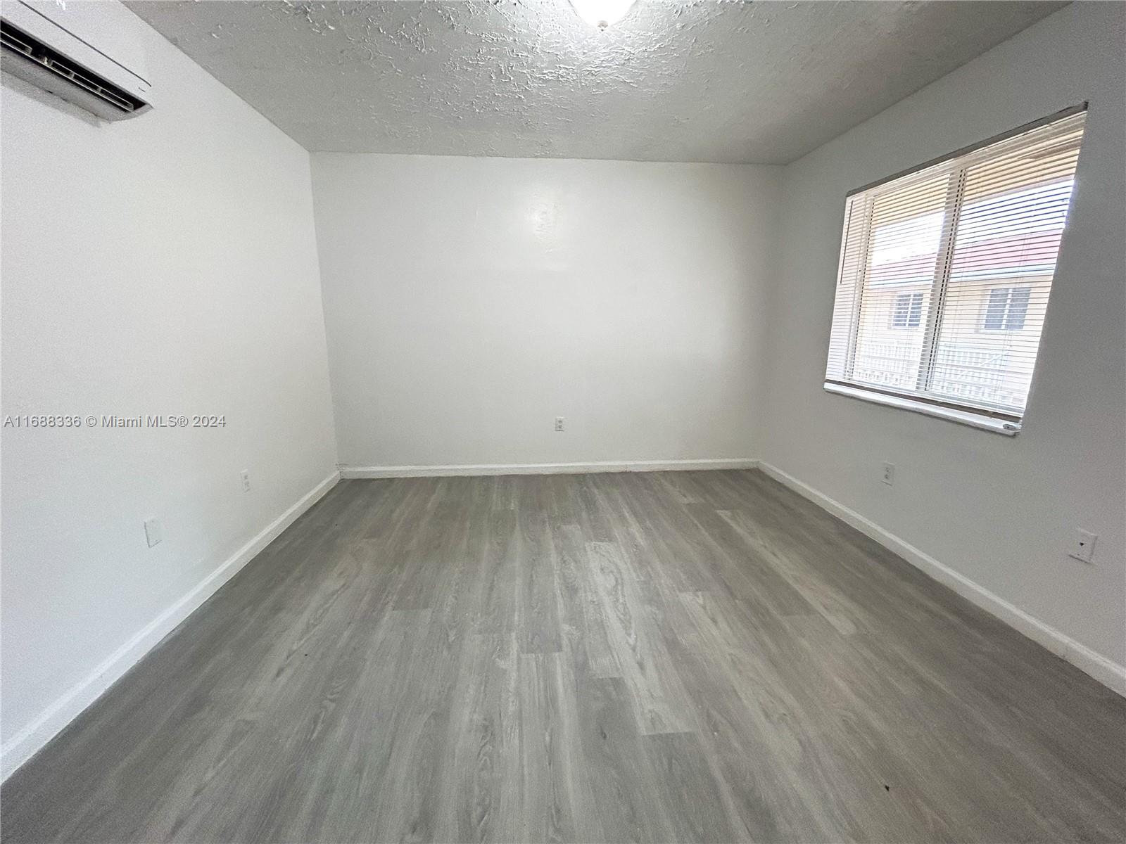 651 Northeast 86th Street, Unit 3 Miami, FL 33138 - Photo 5 of 11 an empty room with wooden floor and windows