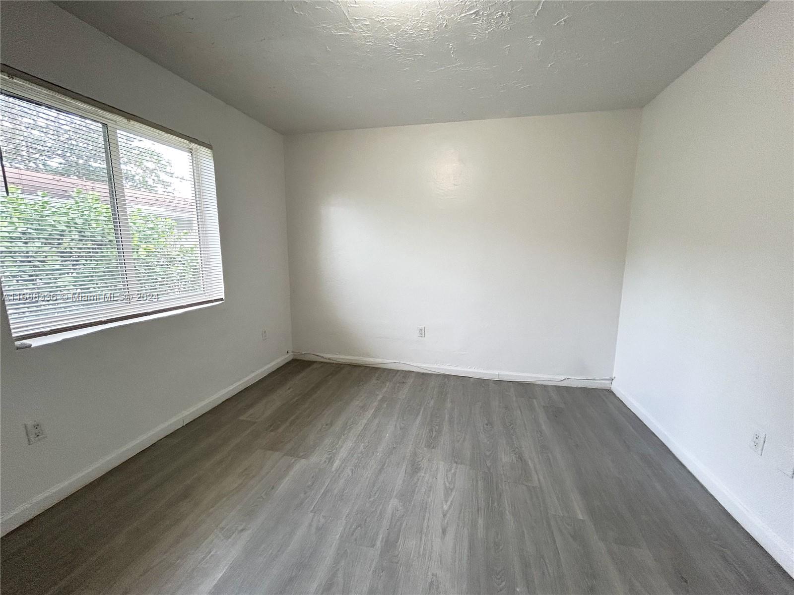 651 Northeast 86th Street, Unit 3 Miami, FL 33138 - Photo 10 of 11 an empty room with wooden floor and windows