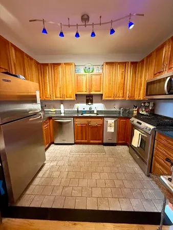 a kitchen with stainless steel appliances granite countertop a sink wooden cabinets and a refrigerator