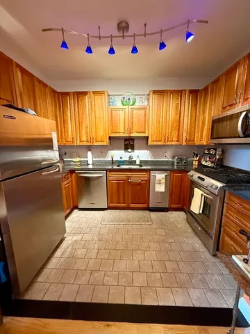 a kitchen with stainless steel appliances granite countertop a sink wooden cabinets and a refrigerator