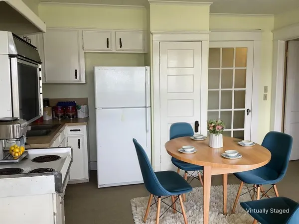 a kitchen with stainless steel appliances a dining table chairs and refrigerator