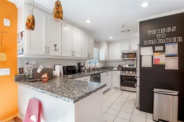 a kitchen with granite countertop kitchen island stainless steel appliances a stove refrigerator sink and cabinets